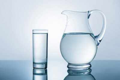 Jug and glass with water on reflecting table